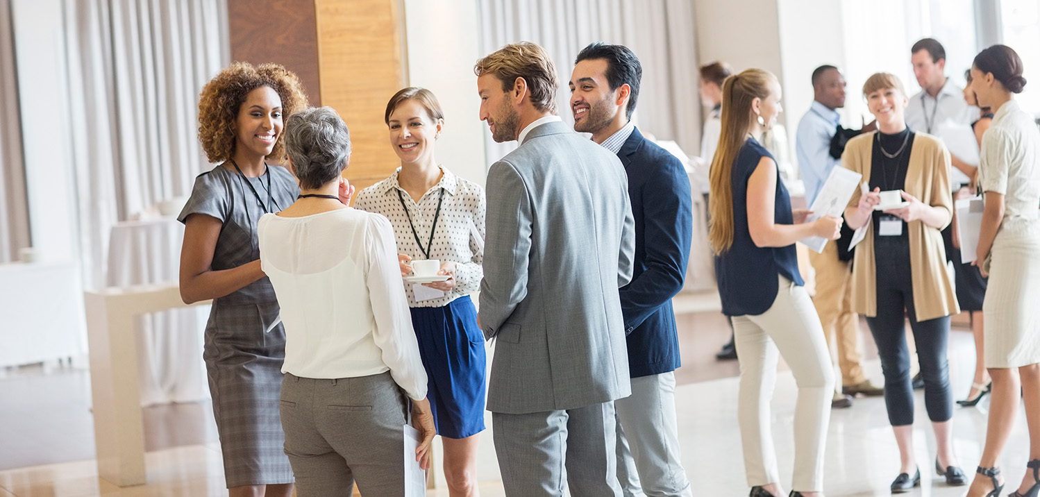 group of diverse conference attendees networking in a lobby of a building